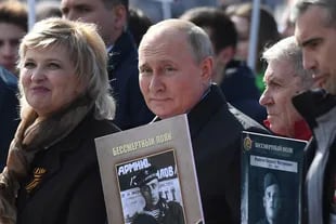 El presidente ruso Vladimir Putin y otros participantes llevan retratos de sus familiares -soldados de la Segunda Guerra Mundial- mientras participan en la marcha del Regimiento Inmortal en la Plaza Roja en el centro de Moscú el 9 de mayo de 2022.