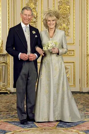 El príncipe de Gales y la duquesa de Cornwall posan en el White Drawing Room del castillo de Windsor para la foto oficial de la boda, la segunda para los dos, celebrada el 9 de abril de 2005 en Windsor. Ella con un vestido blanco de Robinson Valentine, tapado en hilo de seda haciendo juego y un espectacular tocado dorado de Philip Treacy. Él con jacquet.