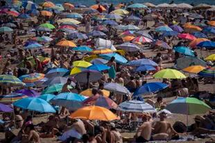 People use umbrellas to protect themselves from the sun on a beach during a hot and sunny day in Barcelona, ​​Spain, Friday, July 15, 2022.