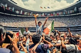 Maradona, con la Copa del Mundo en 1986; su pulgar izquierdo apunta a la bandera de Qatar