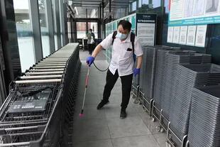 Un trabajador desinfecta canastas de compras y carritos en la entrada de un supermercado en Pekín el 17 de junio de 2020