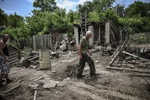 Un hombre camina por el patio de una casa dañada tras un bombardeo en el que murieron dos personas en la ciudad de Lysychansk , en la región oriental ucraniana de Donbass, el 13 de junio de 2022, en medio de la invasión rusa de Ucrania.
