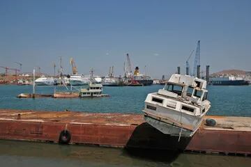 Una lancha abandonada y un barco medio hundido esperan para ser extraídos del agua