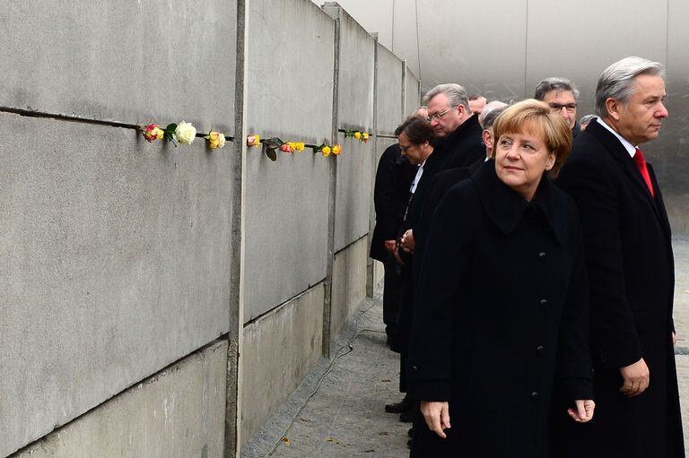 Merkel y el alcalde de Berlín, Klaus Wowereit, se van después de poner rosas en un segmento preservado del Muro de Berlín durante las conmemoraciones del 25 aniversario de la caída, en Bernauer Strasse