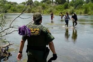 Un agente de la Patrulla Fronteriza observa a un grupo de migrantes cruzar el Río Bravo para entregarse a las autoridades el 15 de junio de 2021, en Del Rio, Texas (Archivo)