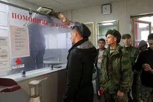 Un oficial ruso verifica la temperatura de los reclutas mientras hacen fila para registrarse en un centro de reclutamiento militar en Volgogrado, Rusia, el sábado 24 de septiembre de 2022. (AP Photo)