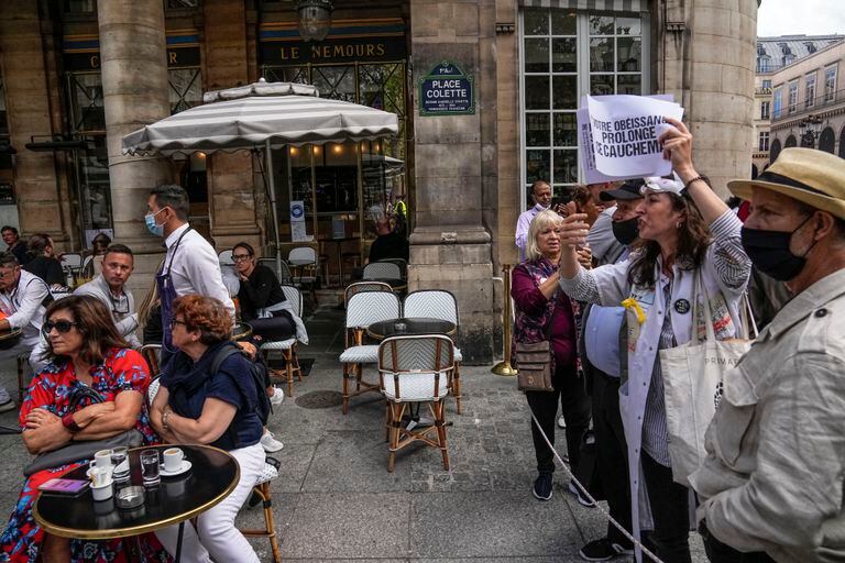 Manifestantes protestan contra el pase especial por Covid-19 junto a un café al aire libre cerca del Tribunal Constitucional de París. (AP Foto/Michel Euler)