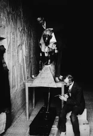 Egiptólos del equipo de Howard Carter en acción. Enero de 1924, en la tumba de Sethos II, que llamaban "el laboratorio". Arthur Mace y Alfred Lucas (sentado) trabajan en una de las dos estatuas de tamaño natural del faraón Tutankamón que encontraron en la Antecámara. (Photo by Hulton Archive/Getty Images)