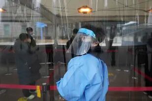 Un sanitario guía a la gente mientras esperan para someterse a una prueba de detección del coronavirus, en un centro de tests improvisado, en Seúl, Corea del Sur, el 16 de diciembre de 2021. (AP Foto/Ahn Young-joon)