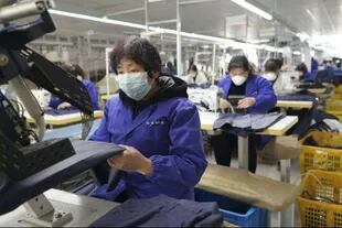 Trabajadores con barbijos en un taller textil de Pekín