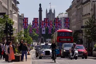 La gente cruza la calle en Piccadilly Circus mientras la calle está decorada con banderas de la Unión, en Londres, el viernes 27 de mayo de 2022