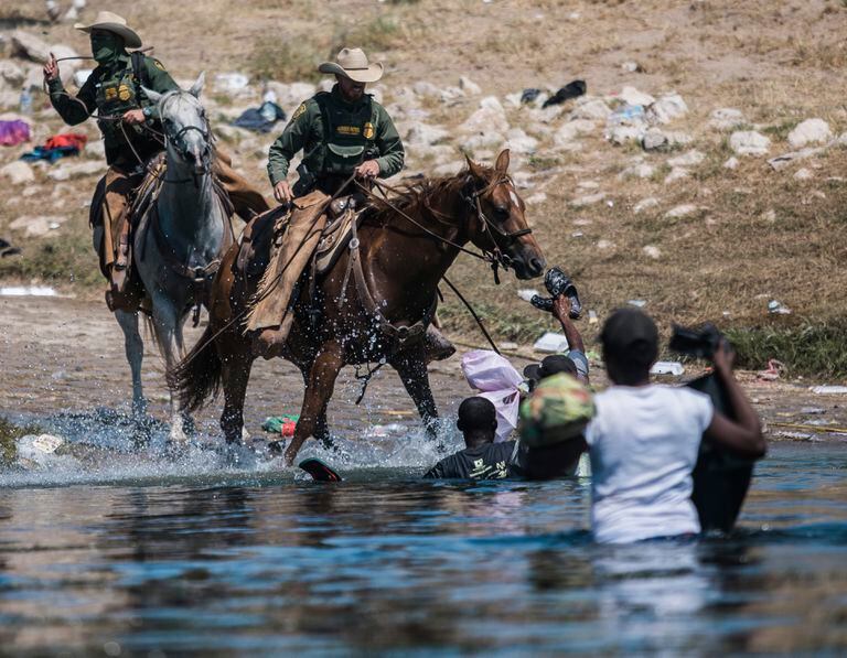 Guardias fronterizos a caballo tratan de impedir el paso de migrantes que cruzan el río Bravo desde Ciudad Acuña, México, a Del Rio, Texas