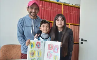 Lionel, junto a su padre Darío y su hermana Brisa, mostrando el álbum improvisado de figuritas
Foto: Fernanda Miranda / Diario de La República