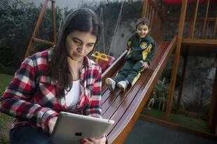 María del Valle Etchaleco chequea las redes sociales mientras su hijo Matías juega 