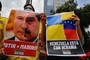 Un activista opositor sostiene un cartel con el rostro del presidente ruso Vladimir Putin y el presidente venezolano Nicolás Maduro durante una protesta contra la invasión rusa en Ucrania