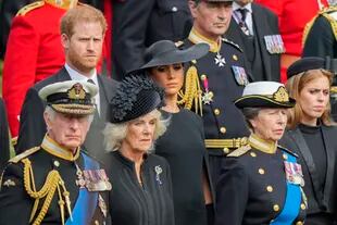 El rey Carlos III de Gran Bretaña, de abajo a la izquierda, Camilla, la reina consorte, la princesa Ana, la princesa Beatriz, Meghan, la duquesa de Sussex y el príncipe Harry observan cómo se coloca el ataúd de la reina Isabel II en el coche fúnebre después del funeral de estado en la Abadía de Westminster