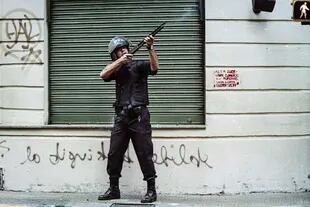 Un oficial abre fuego sobre las ventanas de un edificio el 20 de diciembre de 2001, en los alrededores de la Plaza de Mayo