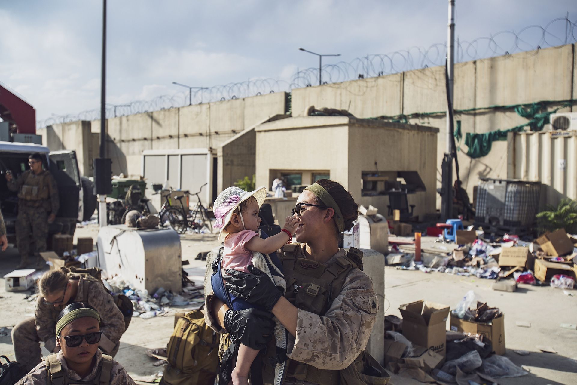 Un miembro de la infantería de marina sostiene a un niño mientras su madre es registrada durante una evacuación en el aeropuerto internacional Hamid Karzai tras la toma de posesión de los talibanes