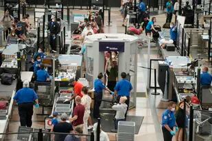 Varios pasajeros pasan por un punto de control de seguridad el 24 de agosto de 2021, en el Aeropuerto Internacional de Denver. (AP Foto/David Zalubowski)