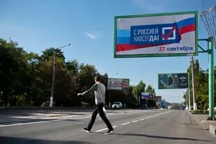 Un hombre cruza una calle con un cartel que dice "Con Rusia para siempre, 27 de septiembre" antes de un referéndum en Lugansk, República Popular de Lugansk controlada por separatistas respaldados por Rusia, este de Ucrania