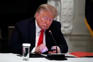 El expresidente Donald Trump mira su teléfono durante una reunión con gobernadores para examinar la reapertura de pequeños negocios, efectuada en el Comedor de Estado de la Casa Blanca en Washington, el 18 de junio de 2020.
