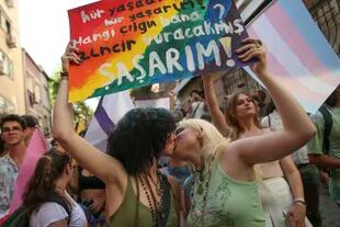 Dos mujeres se besan mientras sostienen una pancarta en turco, que dice "vivo libre. ¿Quién es el tonto que me encadena? Me sorprendería" durante una marcha del Orgullo LGTBQ en Estambul, Turquía, el domingo 26 de junio de 2022. (AP Foto/Emrah Gurel)