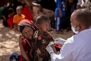 Un enfermero mide el brazo de Nimo Abdi, quien padece diarrea y vómitos y recibe tratamiento por desnutrición, mientras la sostiene su madre Shamis Dhire en una clínica móvil de UNICEF en la aldea de Barare, región somalí de Etiopía, 20 de enero de 2022. La sequía en el Cuerno de África amenaza millones de vidas.  (Mulugeta Ayene/UNICEF via AP)