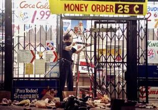 Un policía apunta a un saqueador, en Los Ángeles el 30 de abril de 1992 (Crédito: AP)