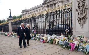 El rey Carlos III y su esposa Camilla miran las ofrendas florales al frente del palacio de Buckingham