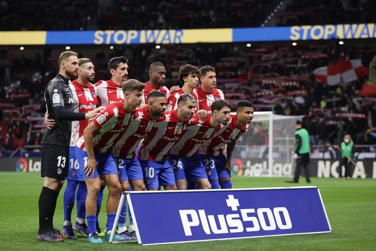 Los jugadores de Atlético de Madrid posan para la foto mientras de fondo los letreros electrónicos del estadio Metropolitano piden "detener la guerra" en azul y amarillo, en apoyo a Ucrania.