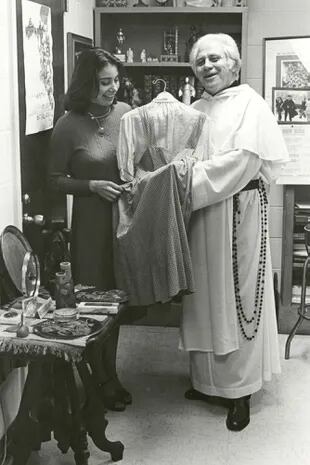 Una fotografía divulgada por la Universidad Católica de América donde aparece el padre Gilbert Hartke y la estudiante Carol Pearson mientras sostienen el vestido de Dorothy en 'El mago de Oz' de 1939