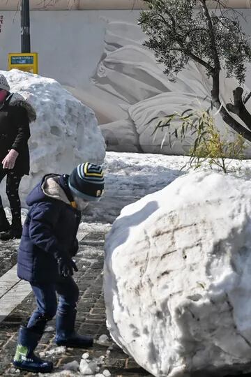 Los niños juegan con enormes bolas de nieve en Atenas el 25 de enero de 2022, después de una tormenta de nieve que interrumpió el tráfico en la capital griega