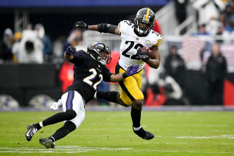 Najee Harris, derecha, de los Steelers de Pittsburgh, corre con el balón mientras que Jimmy Smith, de los Ravens de Baltimore, trata de detenerlo durante la segunda mitad del juego de la NFL del domingo 9 de enero de 2022, en Baltimore. (AP Foto/Nick Wass)