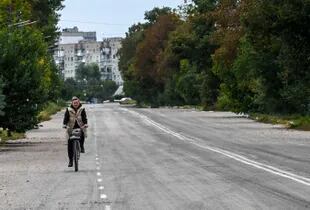 Una mujer anda en bicicleta en la recapturada ciudad de Balaklia, en Kharkiv. (Photo by Juan BARRETO / AFP)