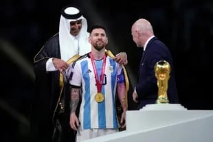 18 December 2022, Qatar, Lusail: Emir of Qatar, Sheikh Tamim bin Hamad Al Thani dresses Argentina's Lionel Messi with traditional Arab bisht ahead of the Trophy presentation as FIFA President Gianni Infantino looks on following the FIFA World Cup Qatar 2022 final soccer match between Argentina and France at the Lusail Stadium. Photo: Mike Egerton/PA Wire/dpa