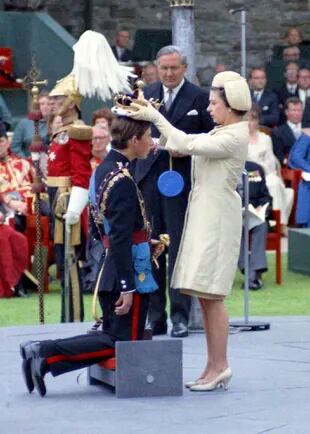 La reina Isabel II corona a su hijo Carlos, príncipe de Gales, durante su ceremonia de investidura el 1 de julio de 1969 en el castillo de Caernafon en Gales, ante la mirada del secretario del Interior británico, James Callaghan