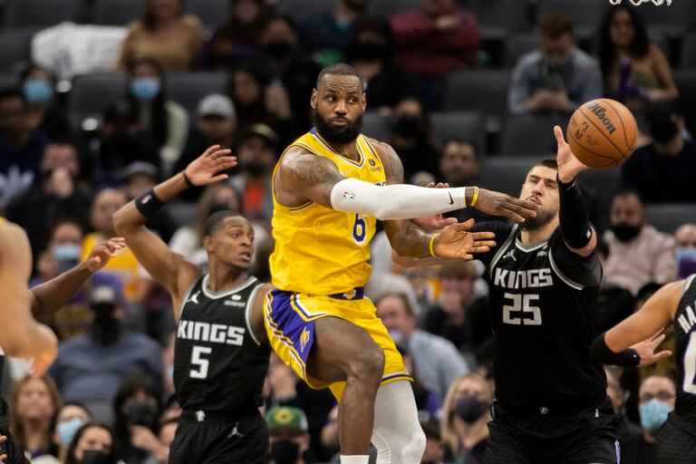 El jugador de los Lakers de Los Ángeles LeBron James (con el 6) pasa el balón mientras los jugadores de los Kings de Sacramento De'Aaron Fox (5) y Alex Len (25) defienden, en la segunda mitad de su juego de NBA en Sacramento, California, el miércoles 12 de enero de 2022. Los Kings ganaron 125-116. (AP Foto/José Luis Villegas)