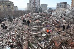 TOPSHOT - Los civiles buscan sobrevivientes bajo los escombros de los edificios derrumbados en Kahramanmaras, cerca del epicentro del terremoto, el día después de que un terremoto de magnitud 7,8 azotara el sureste del país, el 7 de febrero de 2023. - (Foto por Adem ALTAN / AFP)
