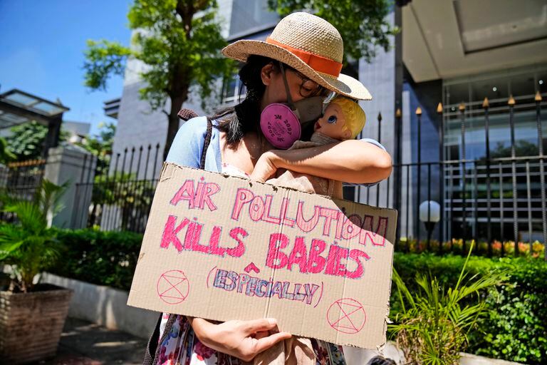 Una activista muestra un cartel con una muñeca que representa a los bebés afectados por la contaminación del aire, durante una protesta ante la Corte del Distrito Central de Yakarta