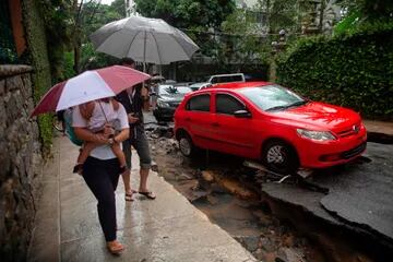 La gente camina por una calle dañada después de fuertes lluvias en el barrio Jardim Botanico en Río de Janeiro