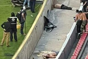 Cuerpos yacientes, inmóviles, en el foso que separa las plateas y la cancha del estadio La Corregidora, de Querétaro.