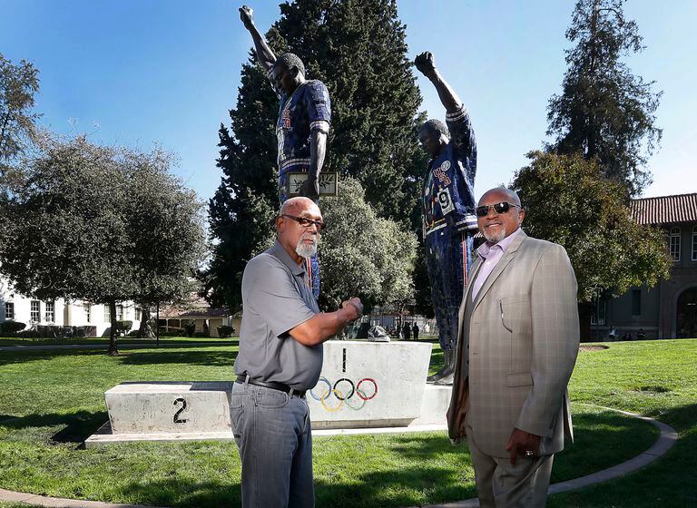 John Carlos (izquierda) y Tommie Smith posan frente a la estatua que los muestra con el puño en alto, la señal de protesta que hicieron en el podio de los Juegos Olímpicos de México 1968. La estatua se encuentra en el campus de la Universidad Estatal de San José, California