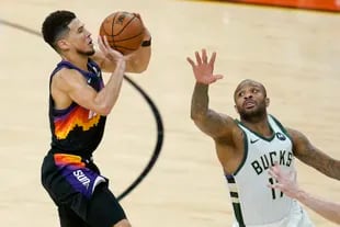 El escolta de los Suns de Phoenix, Devin Booker, dispara ante la defensa del alero de los Bucks de Milwaukee, P.J. Tucker
