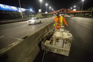Un obrero realiza los últimos trabajos sobre parte del asfalto nuevo en la General Paz
