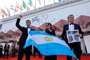 Chino Darin and Ricardo Darin hold the Argentine flag as they walk the red carpet with fellow film producer Victoria Alonso