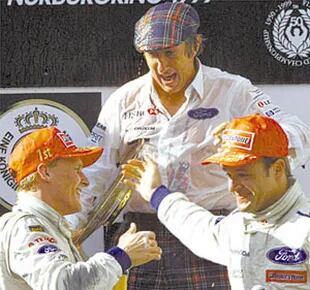 Jackie Stewart, junto con los pilotos Johnny Herbert y Rubens Barrichello en el podio del Gran Premio de Europa 1999, en Nürburgring; el único éxito de la escudería Stewart, que luego se convirtió en Jaguar para ser vendida en 2004 a Red Bull Racing