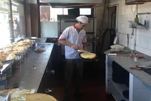 Hernán Castillo mete y saca pizzas del horno en pleno medio día