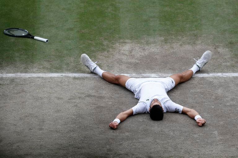 El serbio Novak Djokovic se derrumba mientras celebra después de derrotar al italiano Matteo Berrettini en la final de Wimbledon.