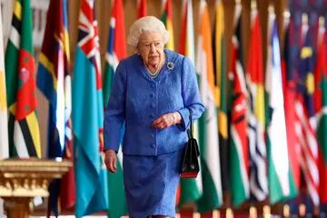 La reina Isabel II de Gran Bretaña pasa frente a las banderas de la Commonwealth en St George's Hall en el Castillo de Windsor, Inglaterra, para conmemorar el Día de la Commonwealth, el 6 de marzo de 2021