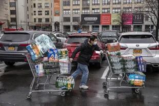 Un comprador empuja sus carritos repletos de provisiones a la salida de un Cotsco, en Brooklyn; ya son 20.000 los infectados en el estado de Nueva York